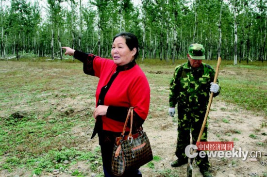 刘玉英，身后是她雇来看护林地的工人。《中国经济周刊》记者 肖翊|摄