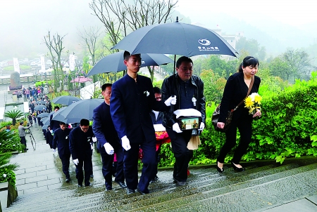 昨日,涪陵区青龙山陵园,市民手捧已逝亲人的灵盒进行免费安葬.