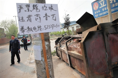 前日，通州区宋庄镇任庄村，一个非法焚烧垃圾点旁挂着警示牌，这个垃圾箱因为多次焚烧，顶部已经变黑。