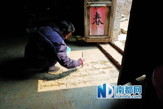 杜深忠蹲在地上用清水写毛笔字。