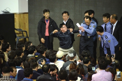 4月19日，韩国珍岛郡体育馆，一名失踪乘客的家属在简报会上对一个警察挥拳相向。图/CFP