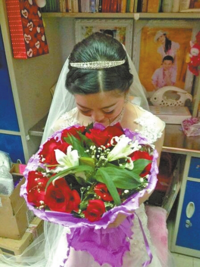 新娘手捧玫瑰，低头闻着花香，感受幸福时刻。　图片由新娘同学提供
