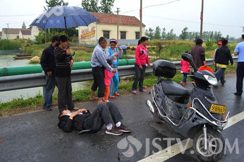 【组图】雨天车手摔倒路边 村民撑伞为其挡雨(组图)