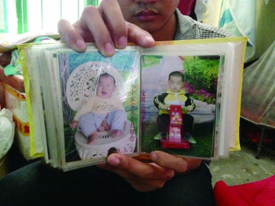 出租房内，李硕展示被打死的大儿子童年照片，沉默不语。记者 赵玲 摄