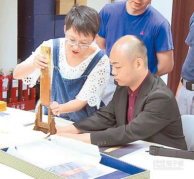 台北故宫人员指导日方“玉鹰纹圭”的正确摆放方式,由于必须防止滑落,且玉石瓷器类较不受水气潮湿影响,故工作人员不需要戴手套。(来源 台湾《中国时报》)