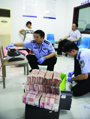 警方在清点缴获的毒资，圆圈中女子为毒枭“慧姐” 特约记者 杨维斌 摄