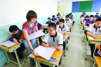 上午,北京第五中学分校考点,考务人员发放语文试卷。周良 文并摄