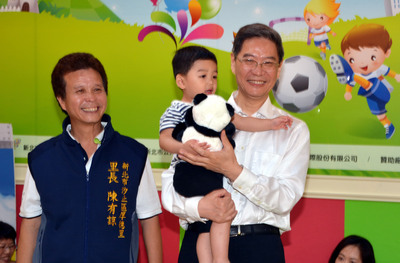 国台办主任张志军26日参访台湾新北市汐止区的公共托育中心，送孩童熊猫玩具当见面礼，并与里长、家长及老师合影。“中央社”