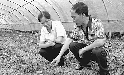 周晓琳(左)向村民了解农作物生长情况。记者 李