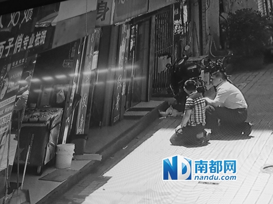 惠城区公安分局副局长谢达文身着便装，像一名家属跪在男童父亲身边，观察店内劫匪情况。视频截图