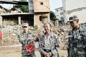 战士石一以格(左一)、毛祖跃(右一)在废墟前和被救老人偶遇,老人十分感谢两位解放军的舍身相救。