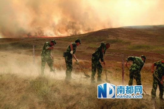 14日,武警新疆边防总队官兵在挖隔离带阻止中哈边界山火蔓延.新华社发