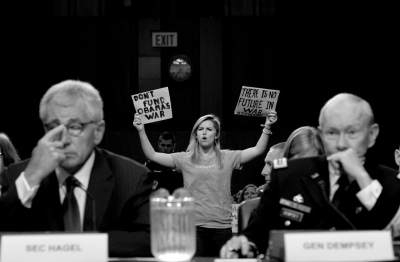 美国国防部长哈格尔（左）和美军参谋长联席会议主席登普西（右）出席参议院军事委员会举行的听证会，反战人士在其身后抗议。新华社发