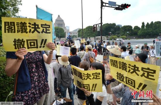 资料图：7月13日，抗议者在日本东京国会大厦前手举标语，大声呼喊反对安倍内阁的口号，并要求安倍内阁撤销此前做出的内阁决定。