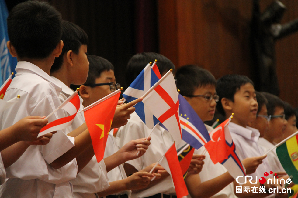 数十位香港十来岁的小学生在香港和平节开幕仪式上挥舞世界各国国旗