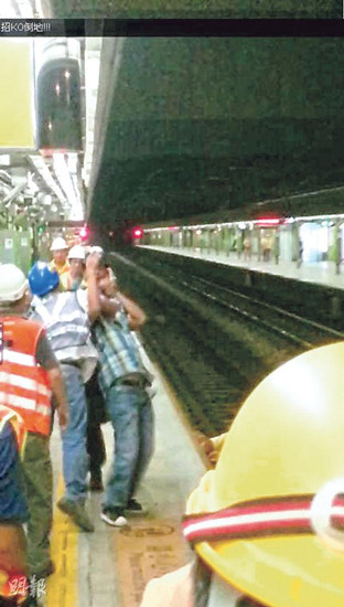 一名港铁工程人员用手箍着男子颈项，终将他压在地上制服。香港《明报》图