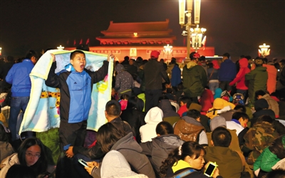 10月1日凌晨，天安门广场，人们穿着厚衣服等候观看升国旗仪式。新京报记者浦峰摄