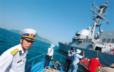 原文配图：2012年4月，一场美越联合救援演习结束后，参加演习的越南民众拍摄美军军舰，一名越南海军官员站在一旁。