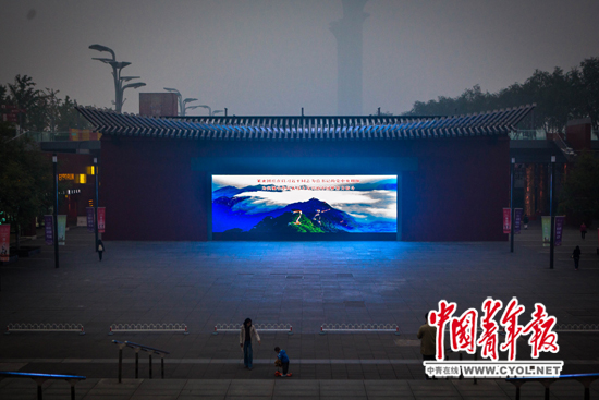 10月9日,北京奥林匹克公园,三三两两的市民在散步。镶嵌在墙壁上的大屏幕在播放着城市宣传片。本报记者 赵迪摄