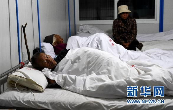 12月6日晚，云南省景谷县永平镇群众推车经过一栋被地震震裂的房屋。 新华社记者 蔺以光