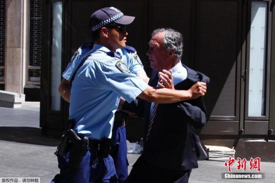资料图：当地时间2014年12月15日，澳大利亚悉尼，一名男子试图进入遭劫持咖啡馆附近的建筑，遭到警方阻拦。 视频：悉尼警方就劫持人质事件召开发布会 来源:中央电视台