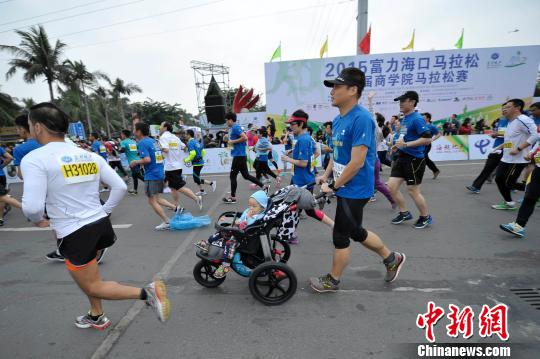 海口马拉松赛有近万人参赛，图为一位父亲推着婴儿车跑步。　骆云飞　摄