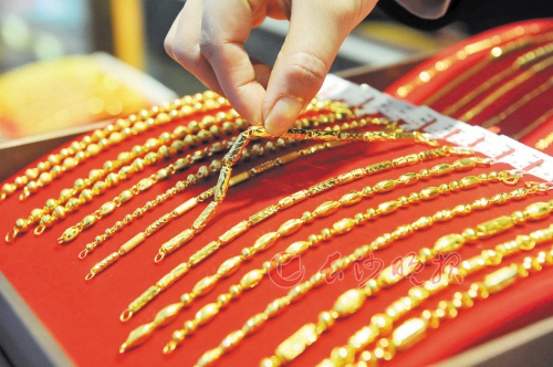 最近的国际金价大幅上涨,亦推升国内金饰品价格。图为一家金店的店员在整理黄金饰品。 新华社发