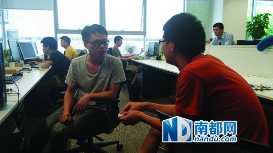 谢锦嵩所在公司加班的场景，谢锦嵩(红色上衣)正在与同事交流。图片由受访者提供