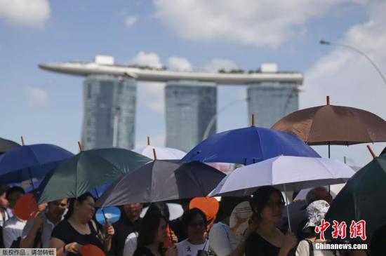 当地时间2015年3月28日，新加坡，民众打着伞排队，等待进入国会大厦吊唁前总理李光耀。