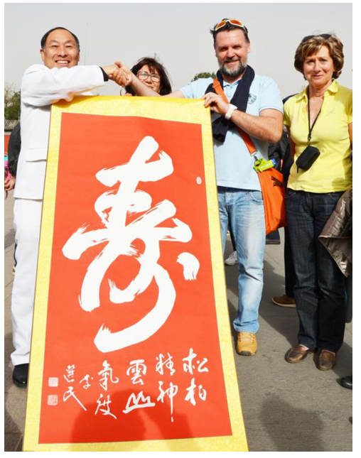 美国外宾接过所购买的李选民书法作品《寿》