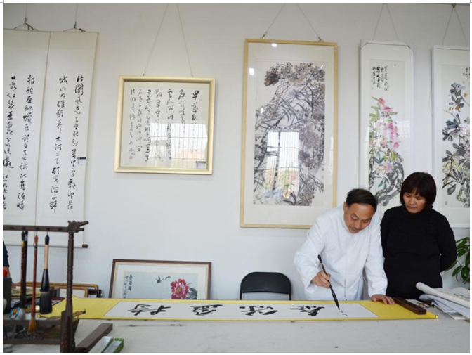 美国外宾接过所购买的李选民书法作品《寿》
