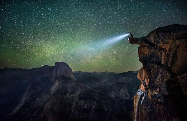 男子头上的照明灯穿过黑暗照亮夜空,点缀着数以千万计的星辰.