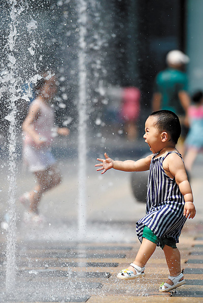 7月12日,一名小朋友在北京三里屯太古里的喷泉戏水.