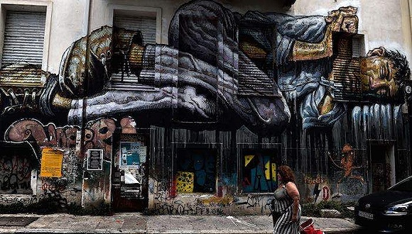 2015年7月11日,雅典,一名女性从一面绘有流浪