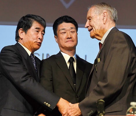 7月19日，在美国洛杉矶，美军战俘劳工代表詹姆斯・墨菲（右）与日本三菱综合材料公司高管木村光及外部董事冈本行夫握手。