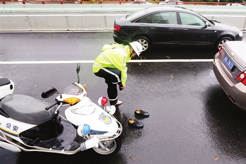 一位交警的皮鞋变成了"雨靴",他只好在路上将鞋中的污水倒出来