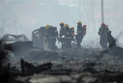 13日，救援人员从爆炸中心附近抬出遇难者遗体。