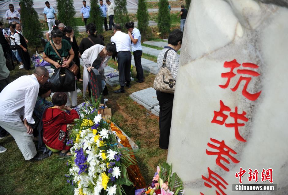 8月31日，位于河北省元氏县的神岩山公墓，工作人员正免费为首批12名抗战老兵完成安葬仪式。据了解，为纪念中国人民抗战胜利暨世界反法西斯战争胜利70周年，神岩山公墓特别设立了“抗战老兵墓区”，并免费提供100个墓位无偿捐献给抗战老兵，让他们能入土为安。墓碑上刻有老兵及其配偶姓氏、生卒时间、部队番号及主要抗战事迹。图为抗战老兵家属、朋友来到墓碑前祭奠。中新社发 翟羽佳 摄