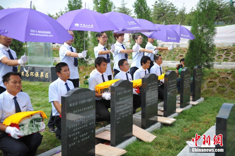 8月31日，位于河北省元氏县的神岩山公墓，工作人员正免费为首批12名抗战老兵完成安葬仪式。据了解，为纪念中国人民抗战胜利暨世界反法西斯战争胜利70周年，神岩山公墓特别设立了“抗战老兵墓区”，并免费提供100个墓位无偿捐献给抗战老兵，让他们能入土为安。墓碑上刻有老兵及其配偶姓氏、生卒时间、部队番号及主要抗战事迹。图为抗战老兵家属、朋友来到墓碑前祭奠。中新社发 翟羽佳 摄