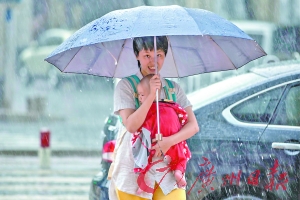 广州市南华东路,天气凉爽,伴着细雨,母亲背着孩子撑伞前行.
