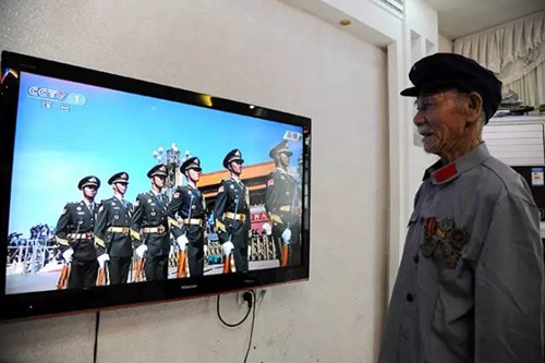 在江西省万载县鹅峰乡多江村,95岁抗战英雄徐桃生正在收看抗战胜利70周年阅兵盛况。徐桃生19岁参军,曾参加过著名的浙江金华保卫战。3日,他特意穿上红军的服装,把珍贵的勋章挂在胸前。看着阅兵场上的年轻人,老人笑得像个孩子。