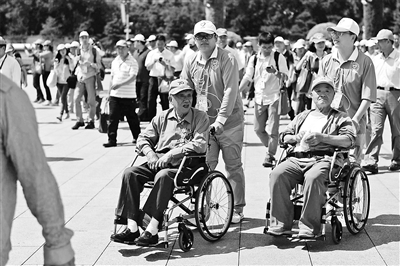 志愿者为腿脚不便的观礼嘉宾推轮椅 摄影/本报记者 魏彤