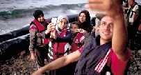 乘坐橡皮艇抵达希腊莱斯沃斯岛的叙利亚难民掏出手机自拍。