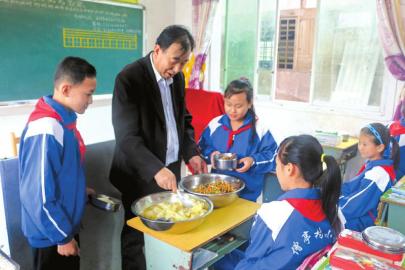 秦可军组织六年级学生吃爱心午餐。