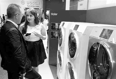 2015柏林國際電子消費品展覽會上，工作人員向觀眾介紹擁有雙滾筒的海爾雙子雲裳洗衣機。本報記者 張雙 攝