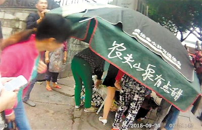 昨日，路人借来小摊的伞遮挡，帮何尧群接生。