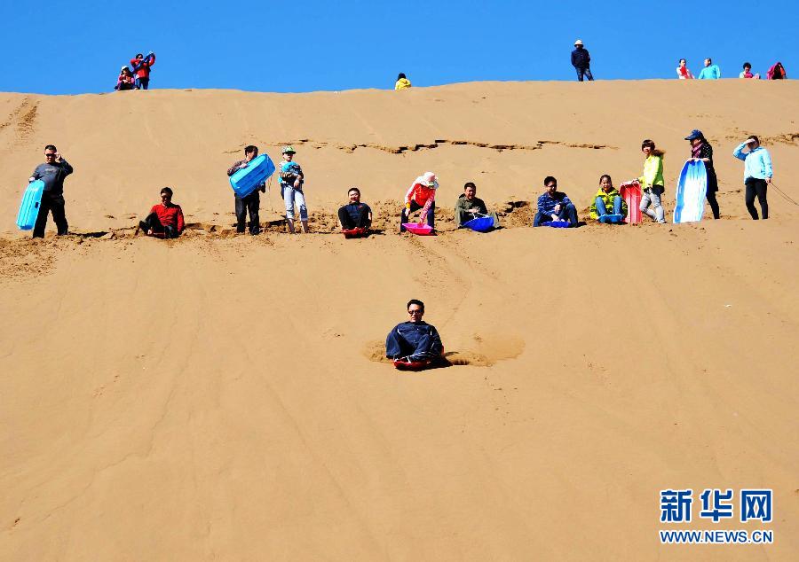 10月3日,游客在木垒县鸣沙山景区体验滑沙. 新华社发(陈鹏)