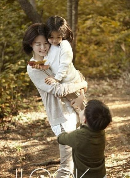 画报中,李英爱将女儿抱在怀里,紧闭双眼,与秋日树林的雅致风景相得