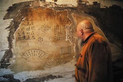 书画大师安云霁正在看曹雪芹故居西屋西墙上的“题壁诗”（复原品，原物已被收藏）。