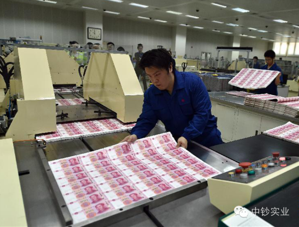 北京印钞有限公司工作人员将印制完成的大张新版百元钞票摆放在机器上